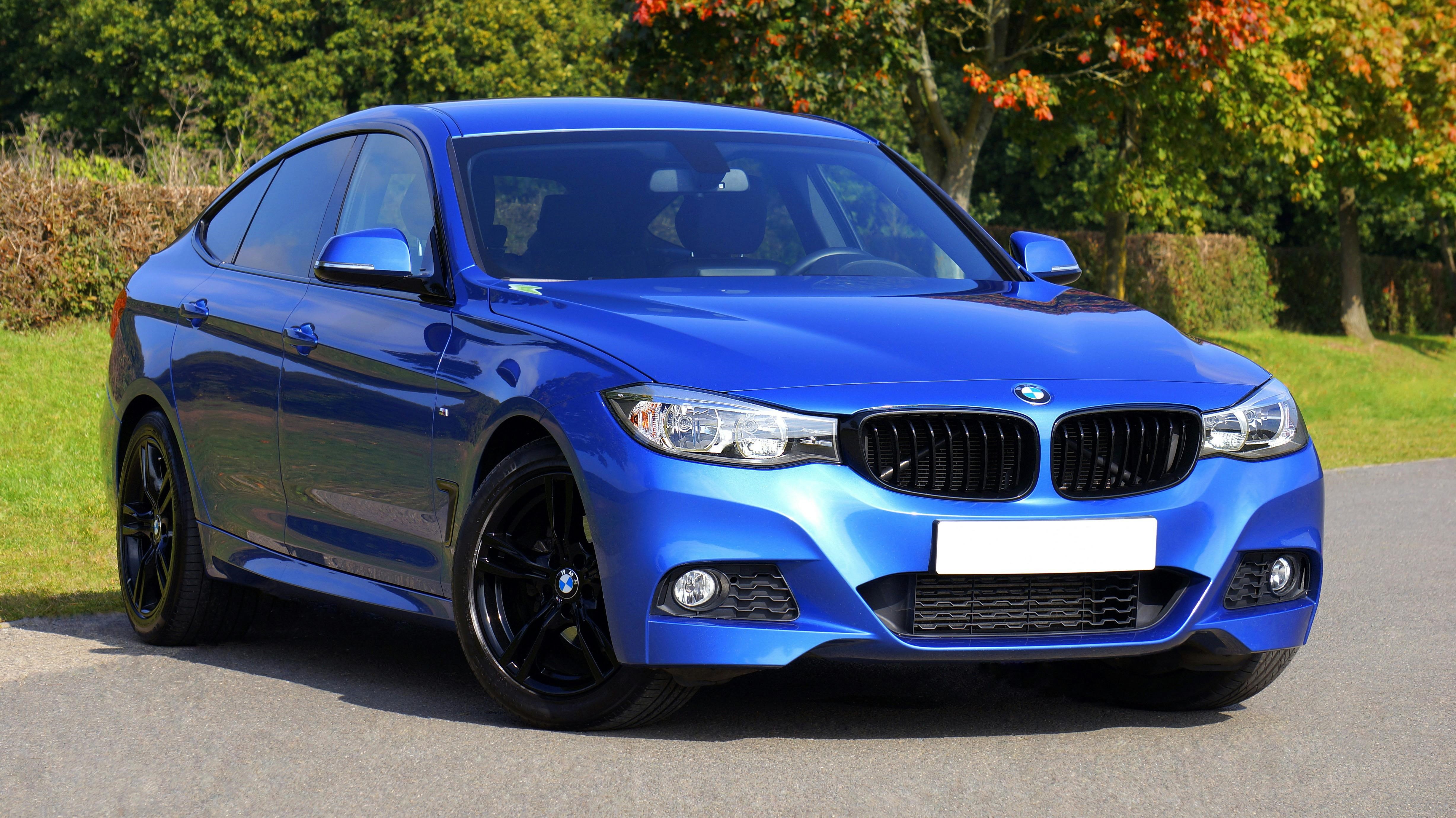 Blue BMW luxury sports sedan parked on road with glossy finish, black alloy rims, and modern automotive design.
